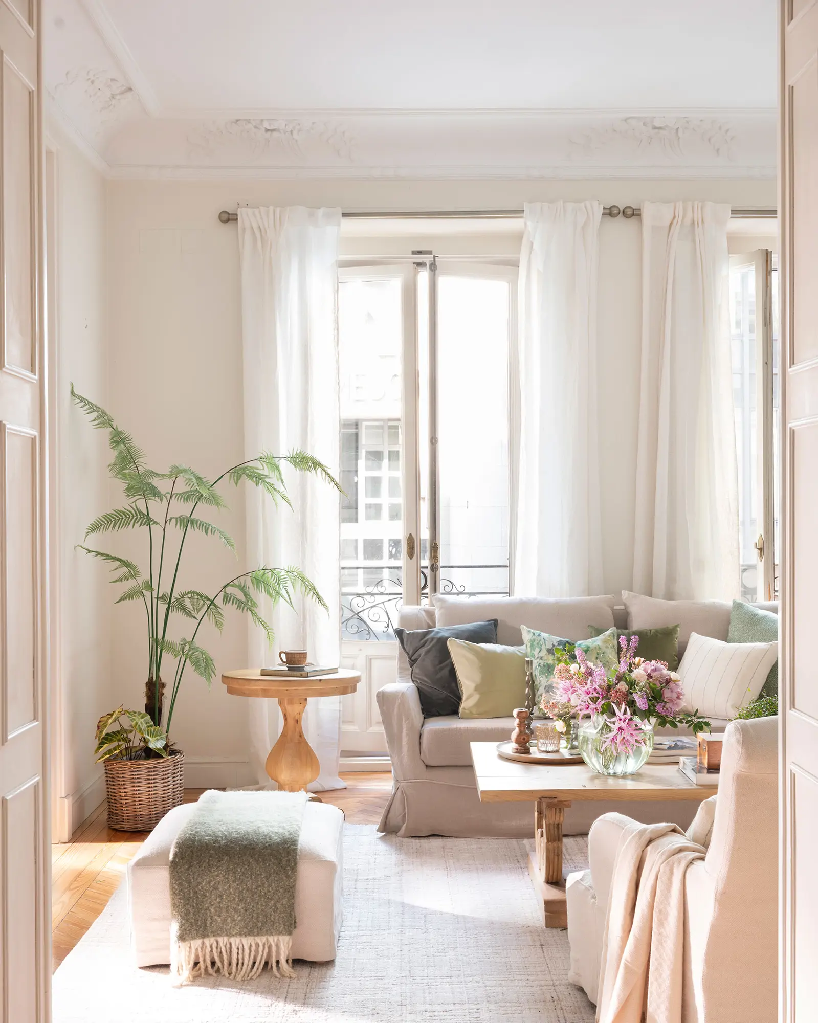 Salón neutro con sofás enfrentados, puf y planta en el rincón.