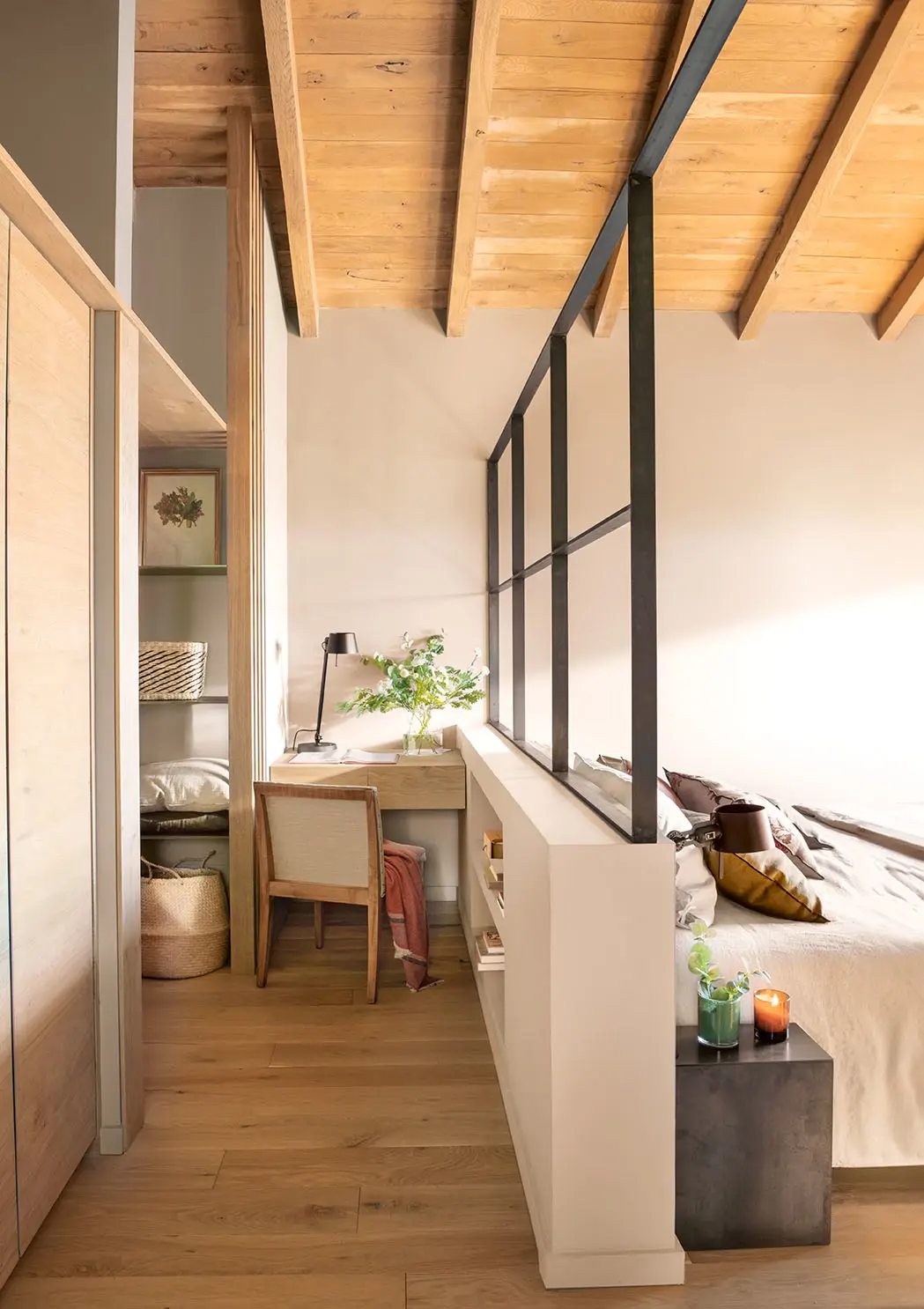 Zona de escritorio tras un medio murete que, a la vez, es el cabecero de la cama.