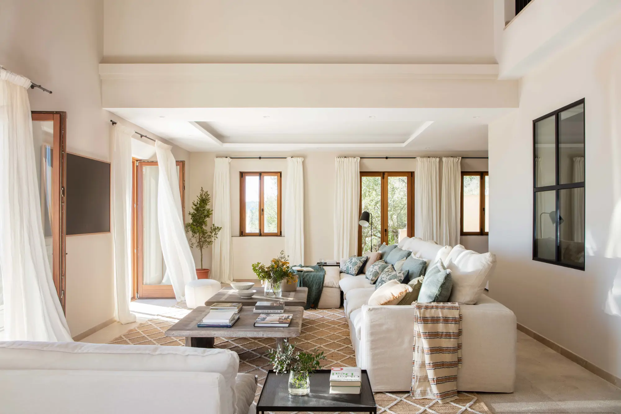 Salón con sofá blanco, cortinas, alfombra y ventana en pared