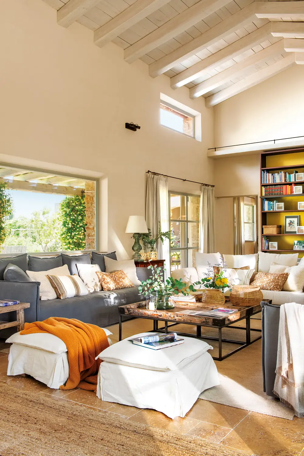 Salón, sofá azul, puf blanco, plaid naranja, mesa de centro, chimenea, estantes, librerías, salón abierto