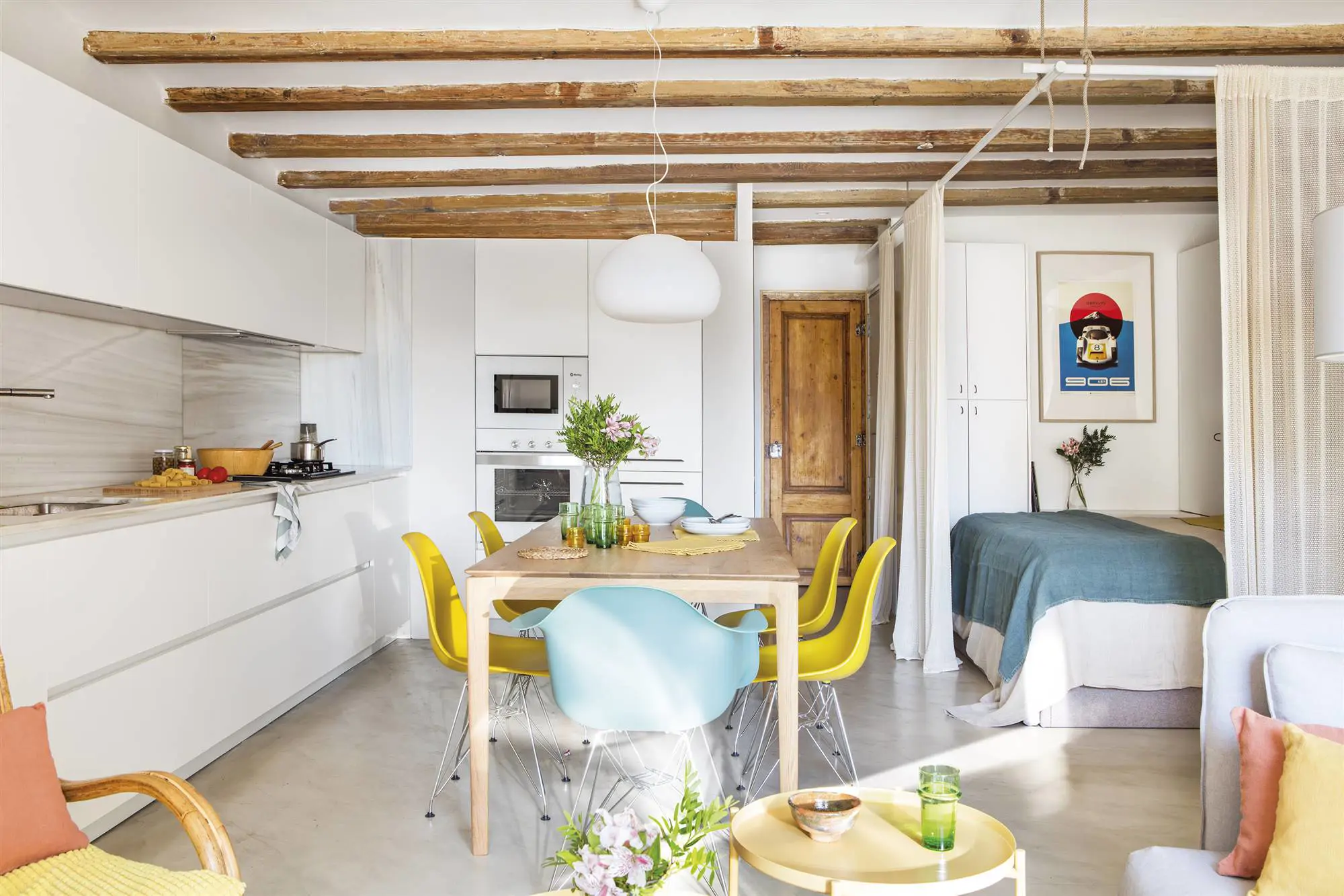 Cocina blanco con mesa de comedor de madera y sillas amarillas y azules