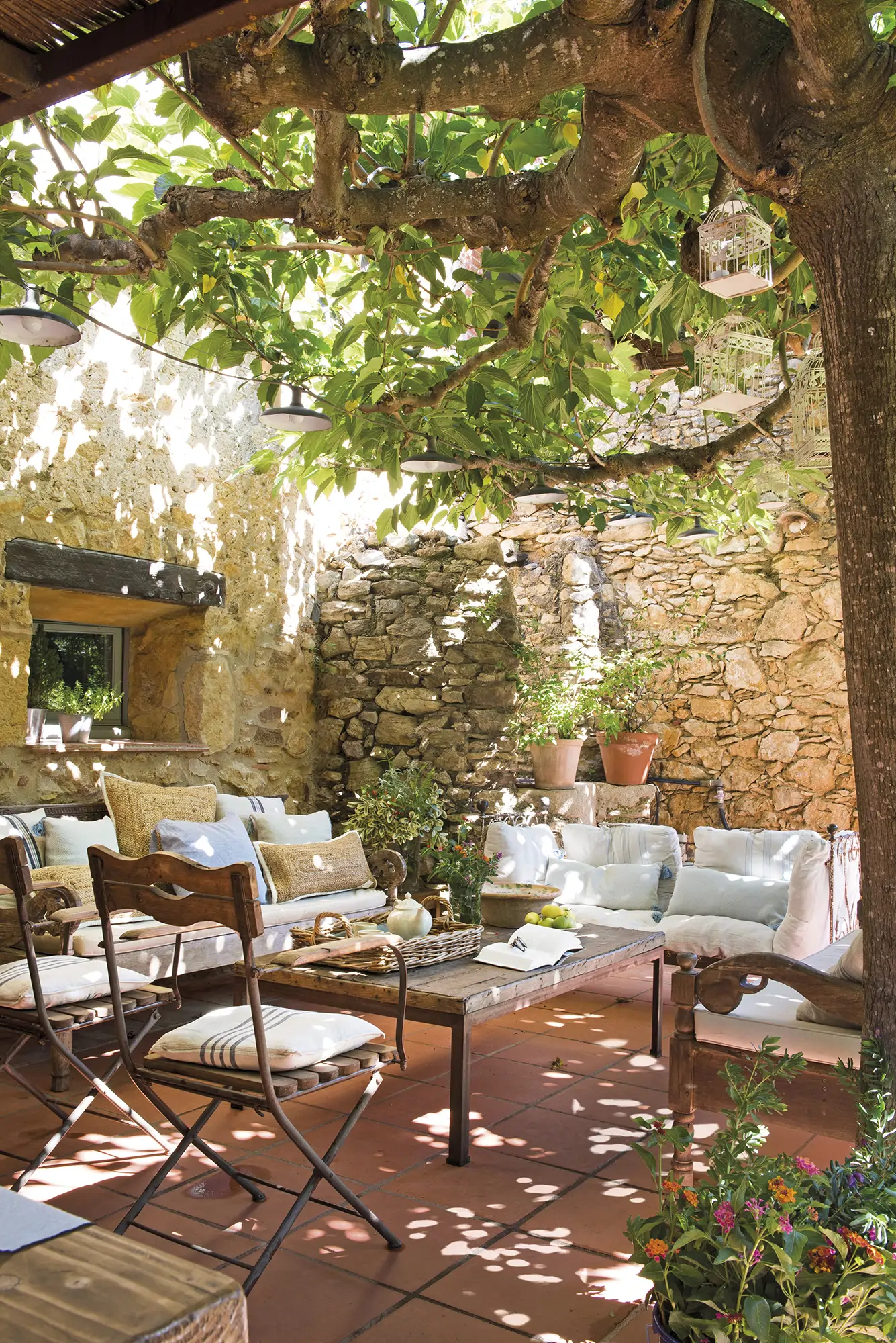 Porche de estilo rústico con sillas y mesa bajo árbol