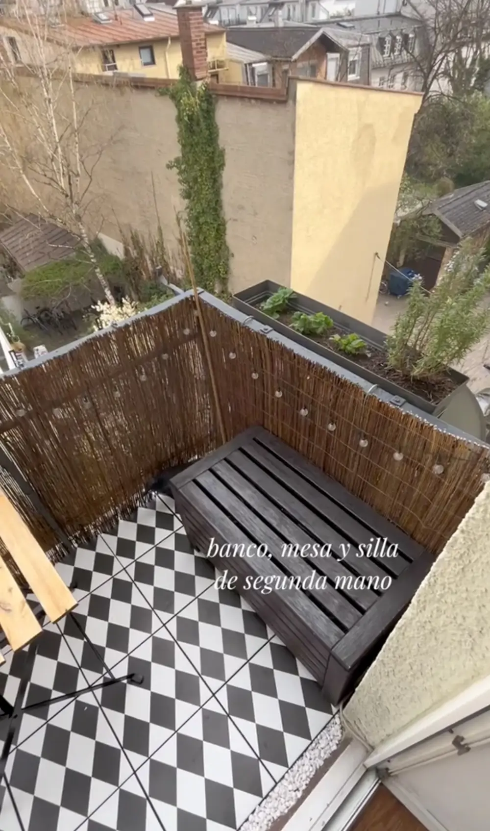 Balcón pequeño con banco de madera y suelo con baldosas geométricas