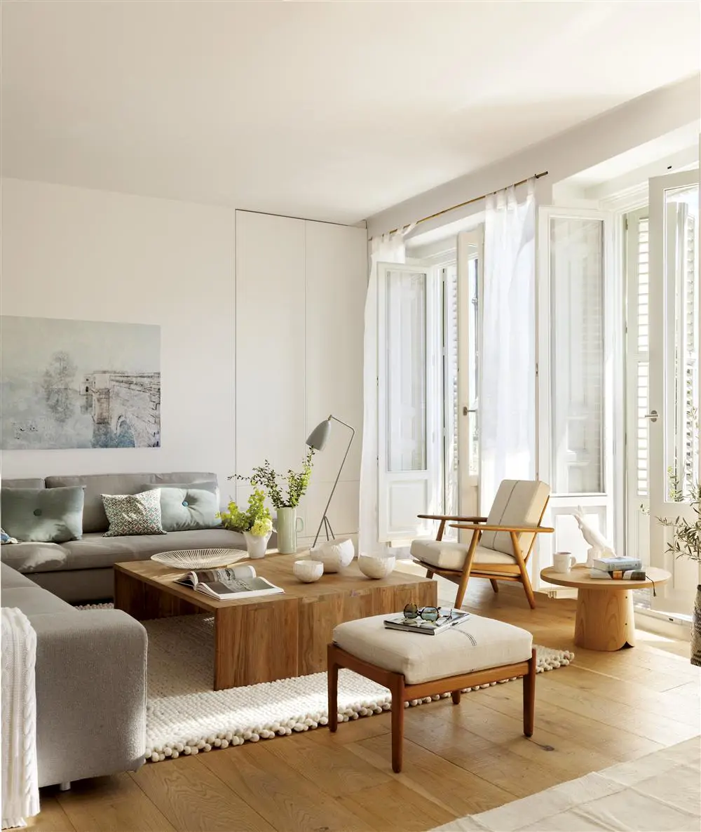 Salón pequeño con grandes ventanales, paredes lisas y blancas y suelos de madera